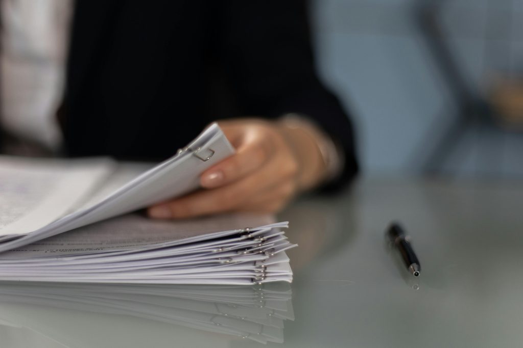pexels photo 6077600 6077600 Close-up of a professional organizing a stack of documents on a desk.