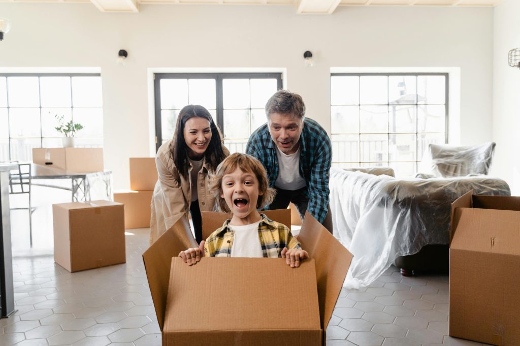 pexels photo 7414954 7414954 Family playing with cardboard boxes during move into a new home, symbolizing joy and togetherness.